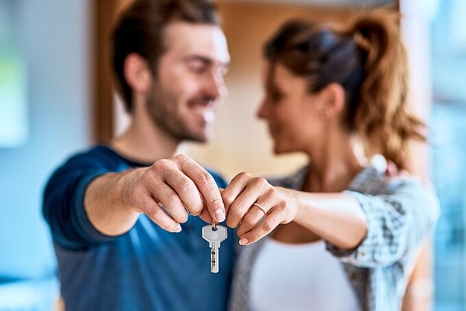 Pärchen schaut sich an und hält gemeinsam einen Haustürschlüssel vor sich