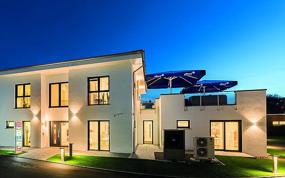 Außenansicht des beleuchteten Musterhauses Günzburg von allkauf, Ansicht am Abend