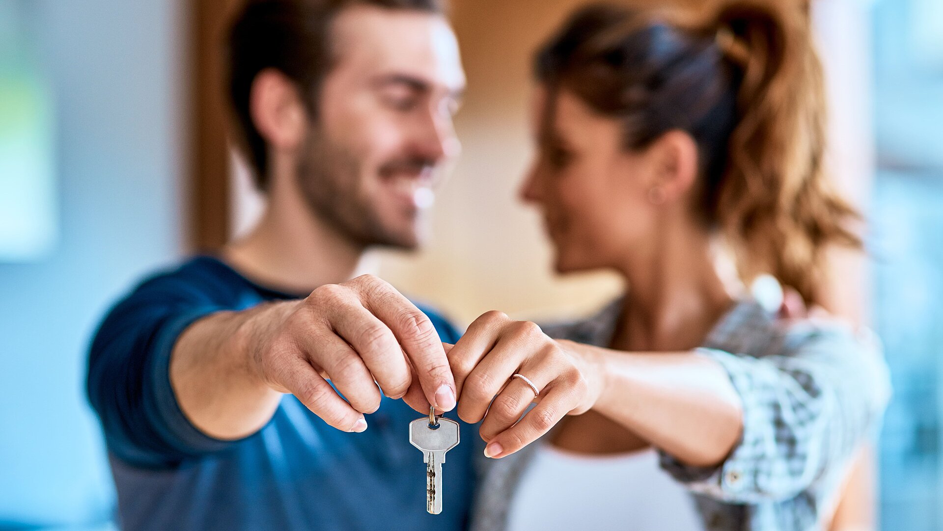 Pärchen schaut sich an und hält gemeinsam einen Haustürschlüssel vor sich