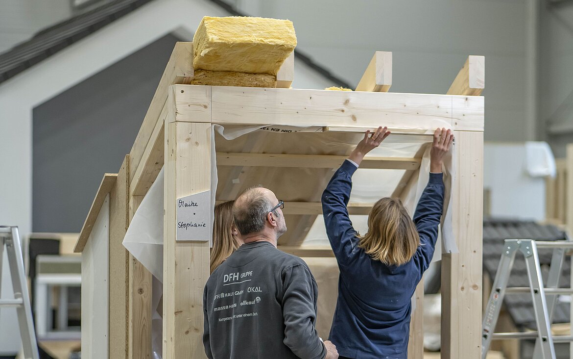 Zwei Teilnehmer der Ausbau-Akademie üben den Innenausbau unter dem Dach